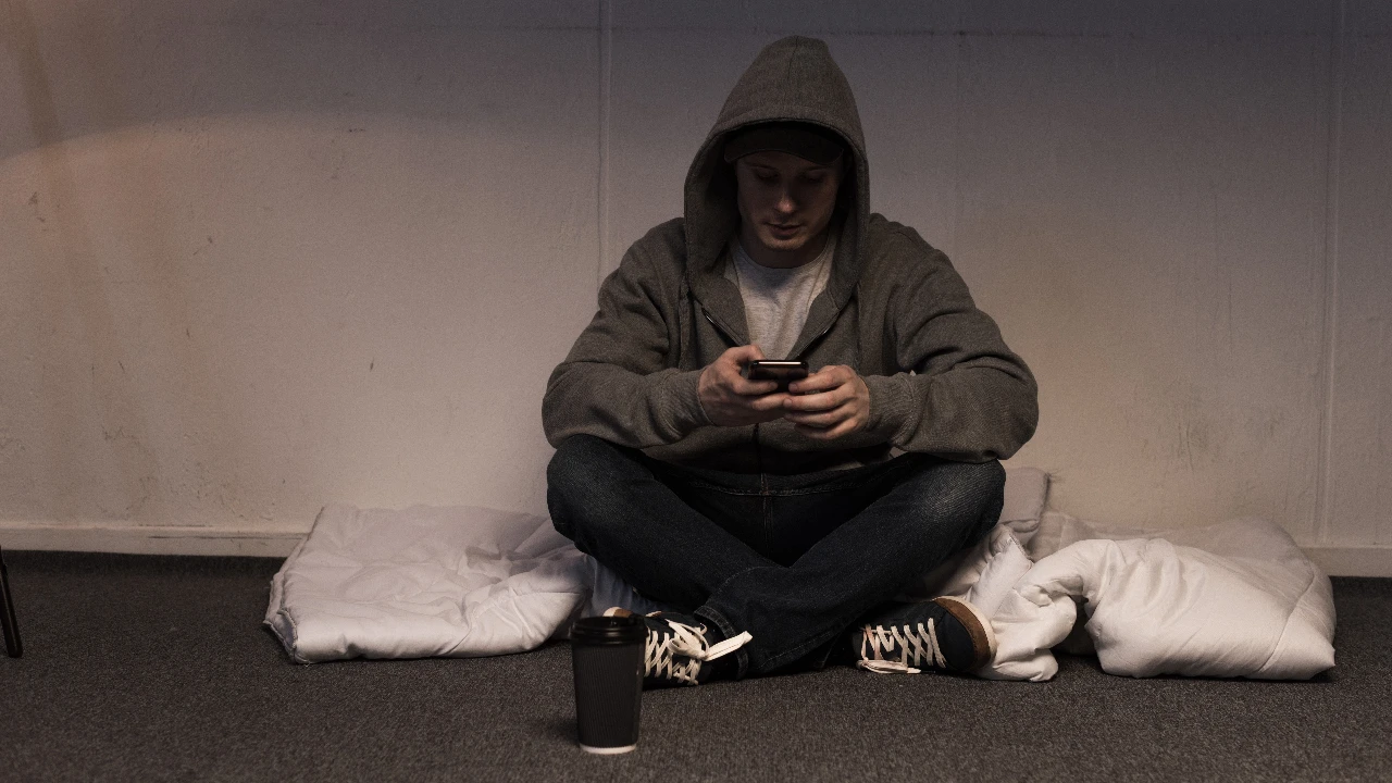 Jovem no quarto com telemóvel @Envato
